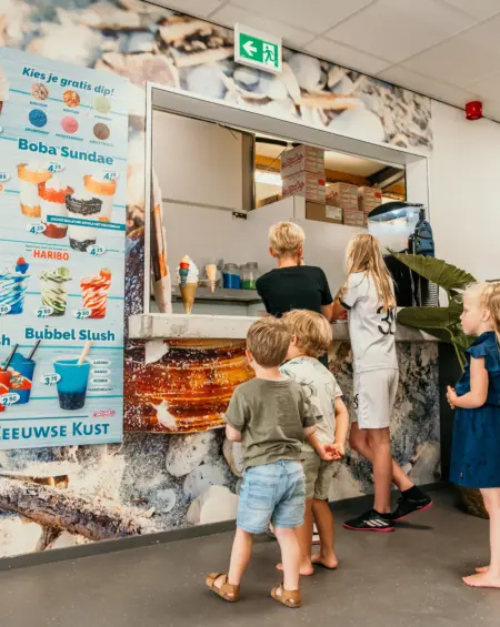 Met de voetjes in de zandkleurige vloer en een verlangende blik op het menu – genieten begint hier bij het familieresort in Zeeland
