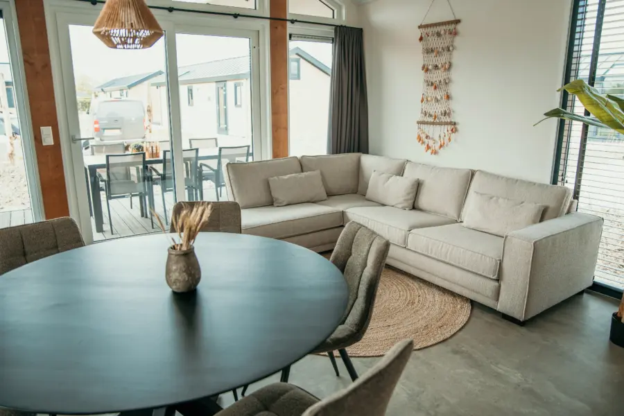 Een ruime, lichte woonkamer met een fijne hoekbank en een open verbinding naar het terras – perfect om samen te genieten van een vakantie in de Zeeuwse natuur
