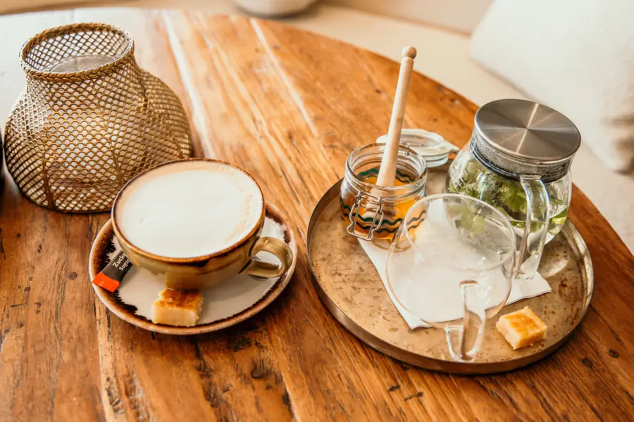 Cappuccino en verse muntthee met honing sfeervol geserveerd op een houten tafel in het restaurant van Strandpark De Zeeuwse Kust