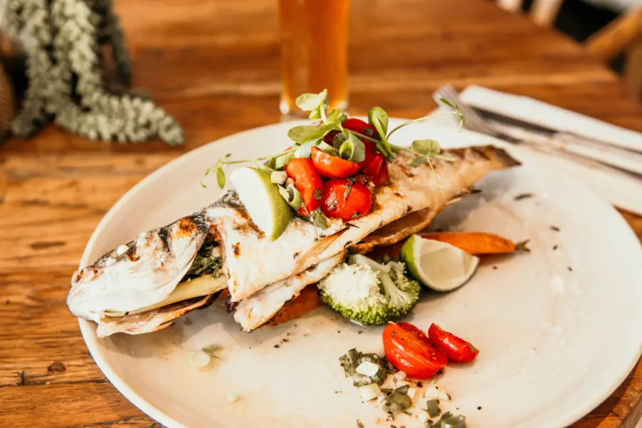 Gegrilde hele vis met verse groenten limoen en kruiden stijlvol gepresenteerd in het restaurant van Strandpark De Zeeuwse Kust